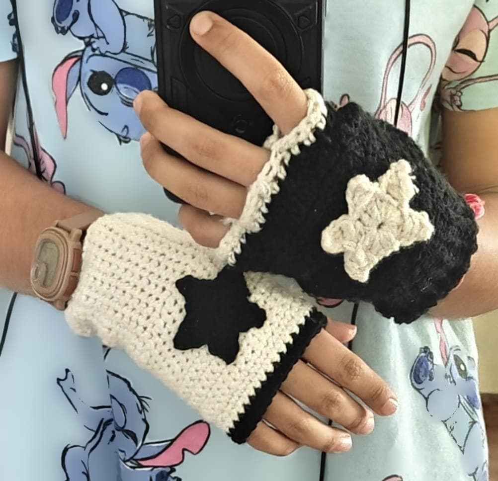 Handmade mismatched fingerless crochet gloves, one cream with a black star and one black with a cream star